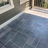 Residential porch with dark grey tiled concrete flooring, clean lines, and a light grey house exterior.